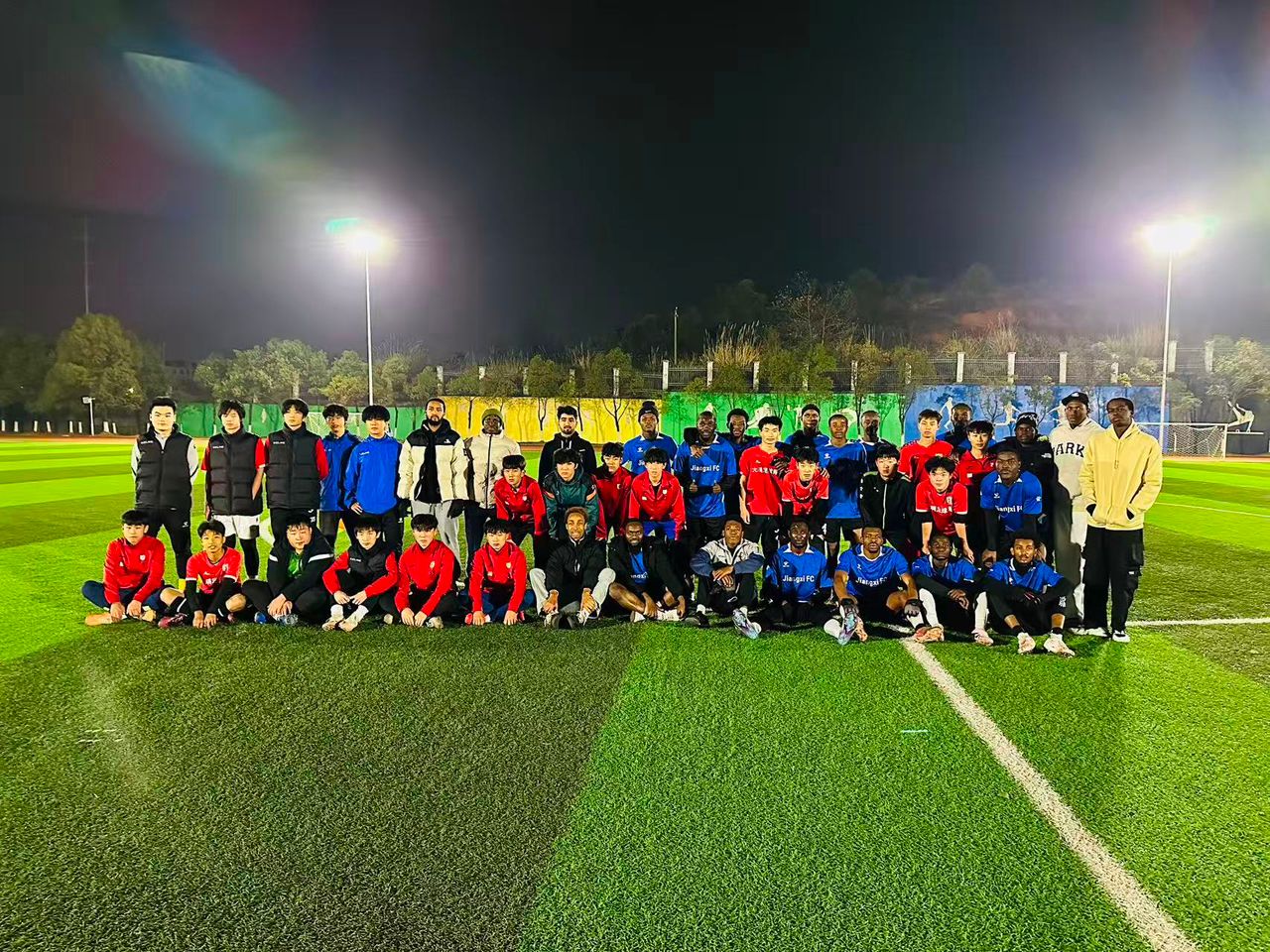 International student football team posing on the field at night